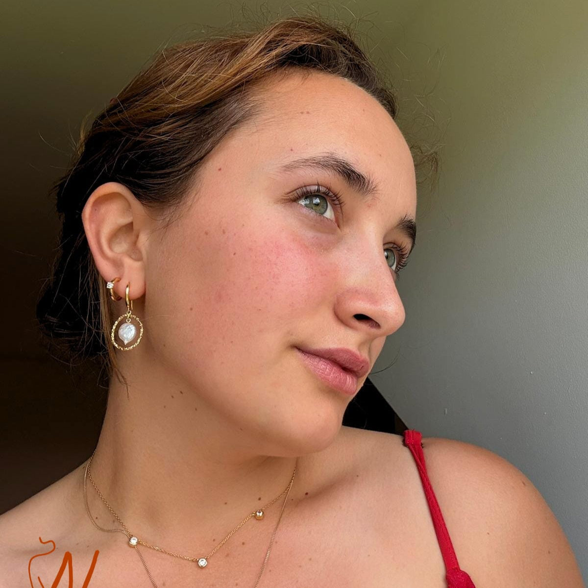 Woman wearing gold jewelry with a neutral background