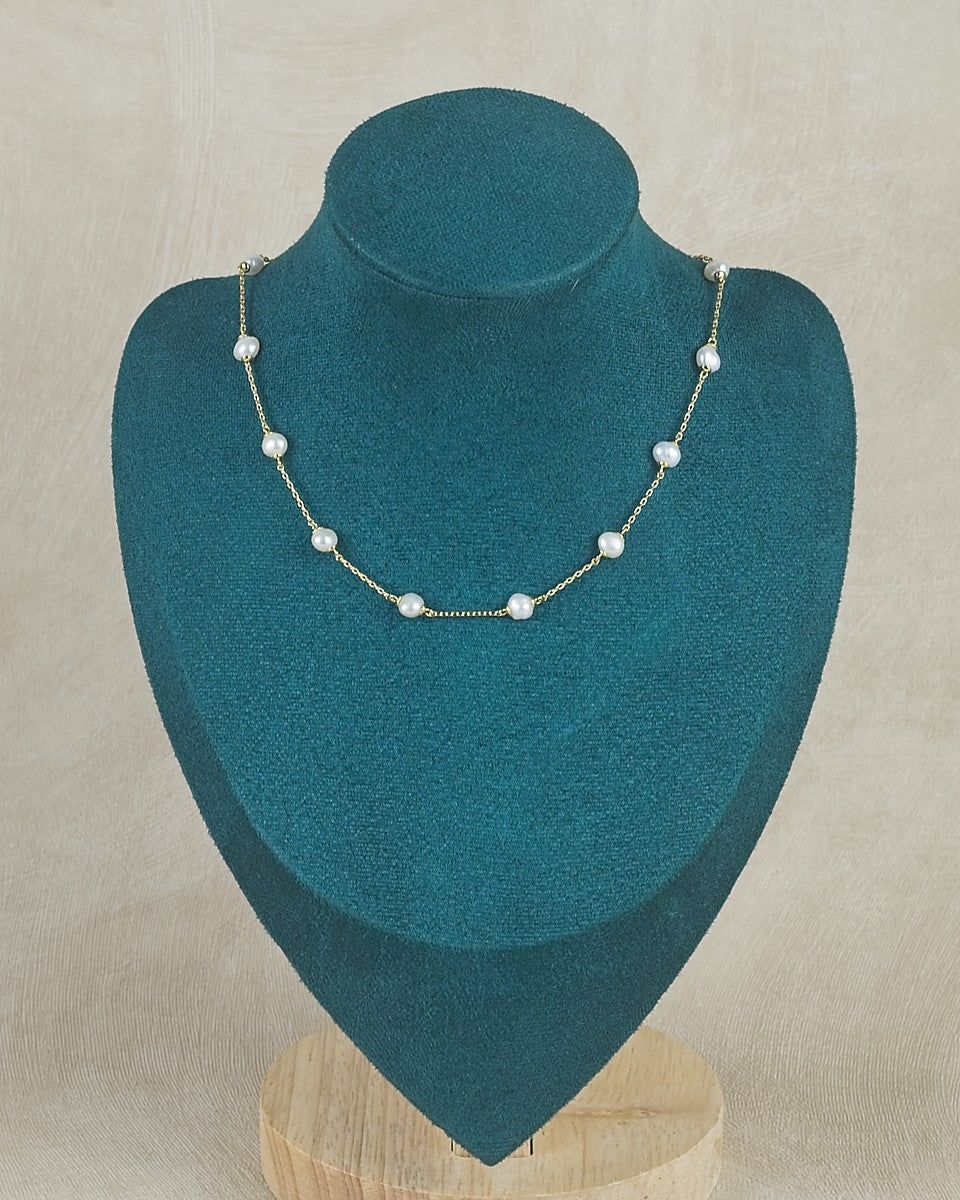 Pearl necklace on a teal jewelry display stand against a beige background
