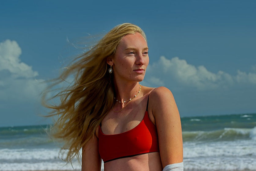 Woman in a red bikini standing on a beach with ocean waves in the background