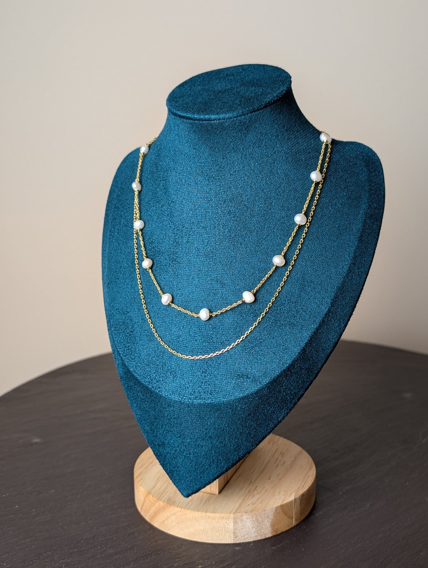 Maris Necklace by Nudie – studio photo showing freshwater pearls on a fine gold chain, layered with a second twisted strand, displayed on a green and wooden mannequin.