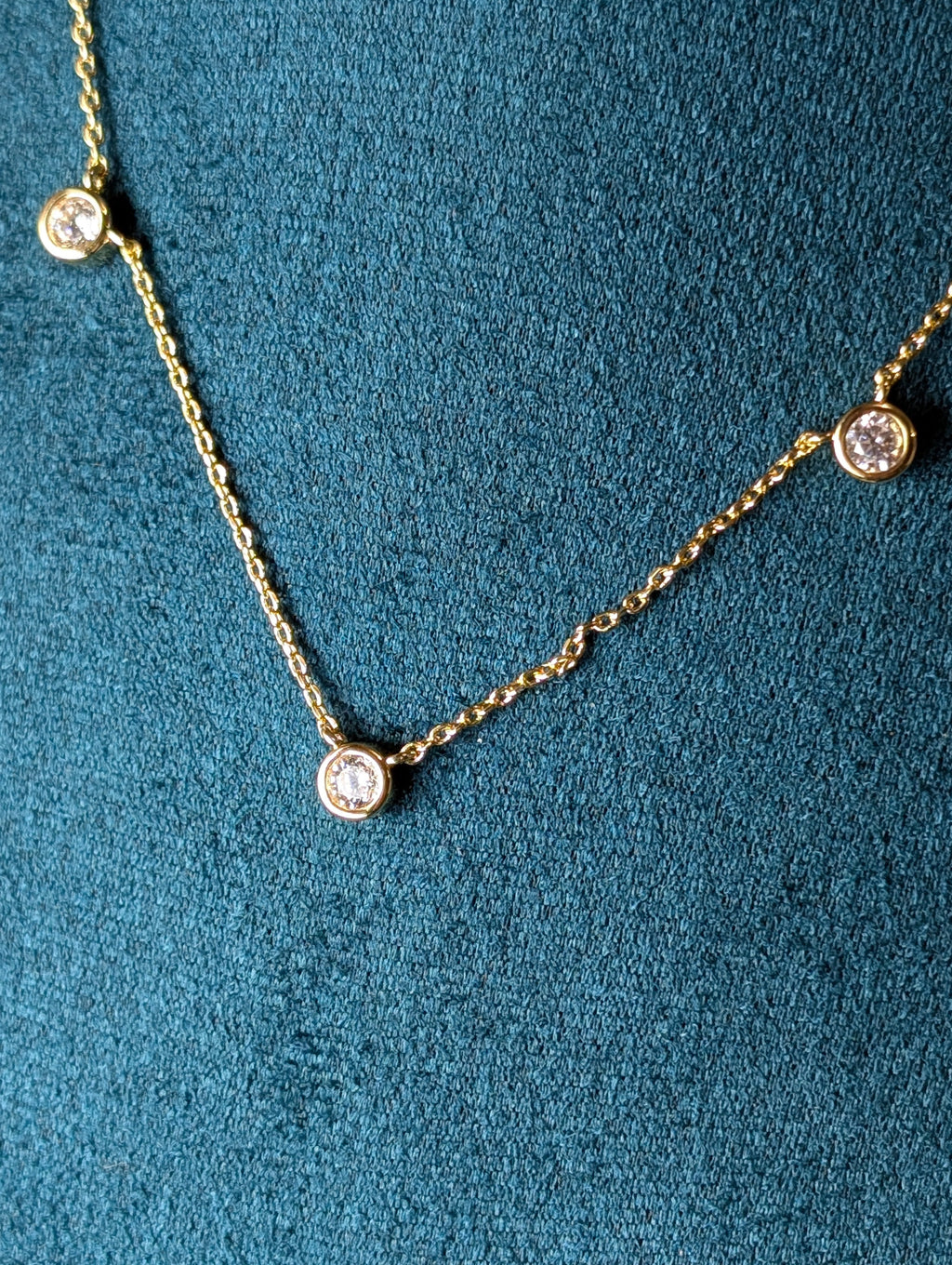 Avalon Necklace by Nudie – close-up studio photo showing hammered gold pendant on green mannequin background, highlighting texture and delicate chain detail.
