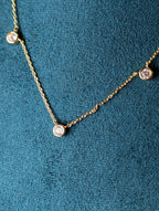 Avalon Necklace by Nudie – close-up studio photo showing hammered gold pendant on green mannequin background, highlighting texture and delicate chain detail.