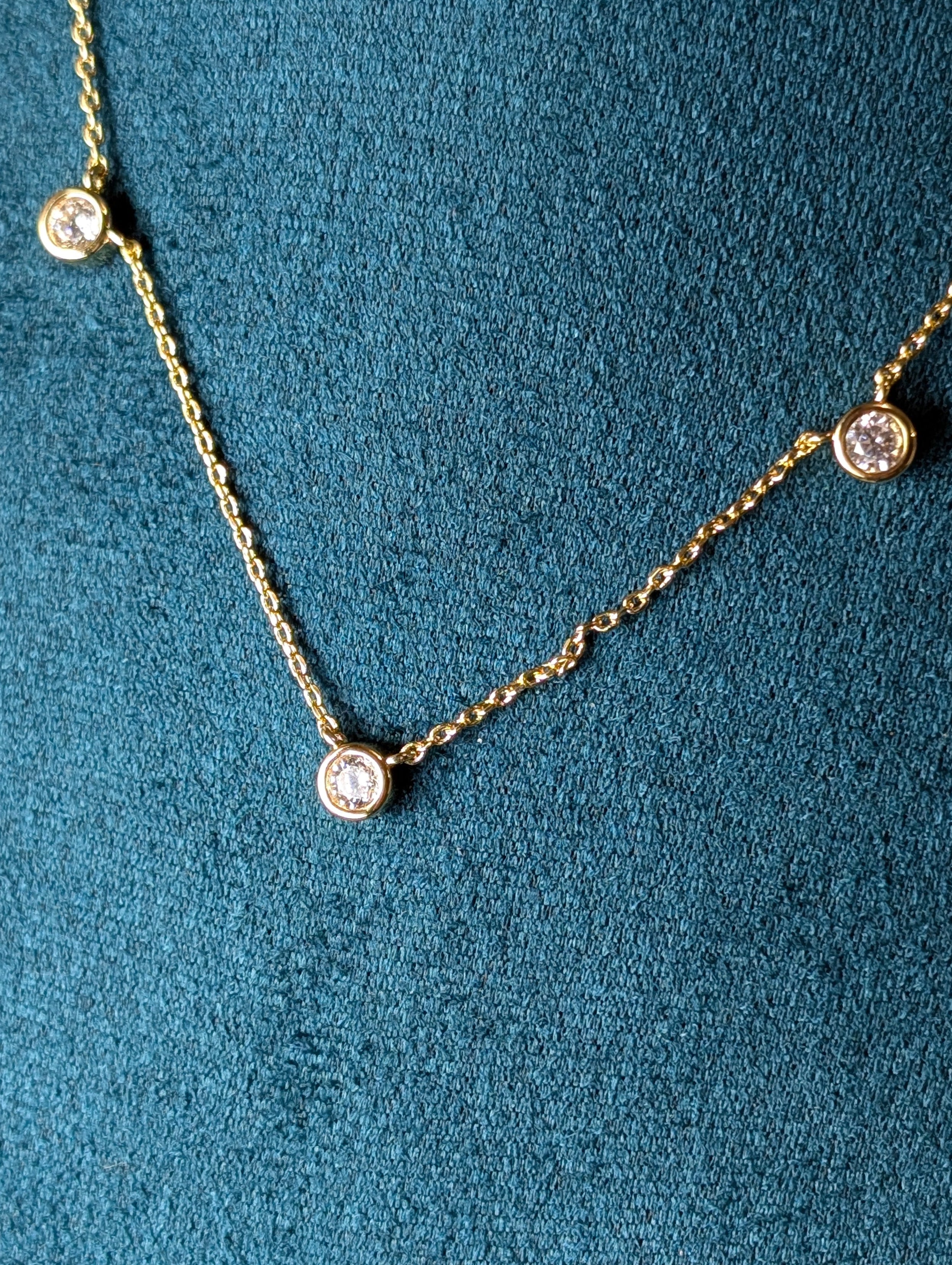Avalon Necklace by Nudie – close-up studio photo showing hammered gold pendant on green mannequin background, highlighting texture and delicate chain detail.