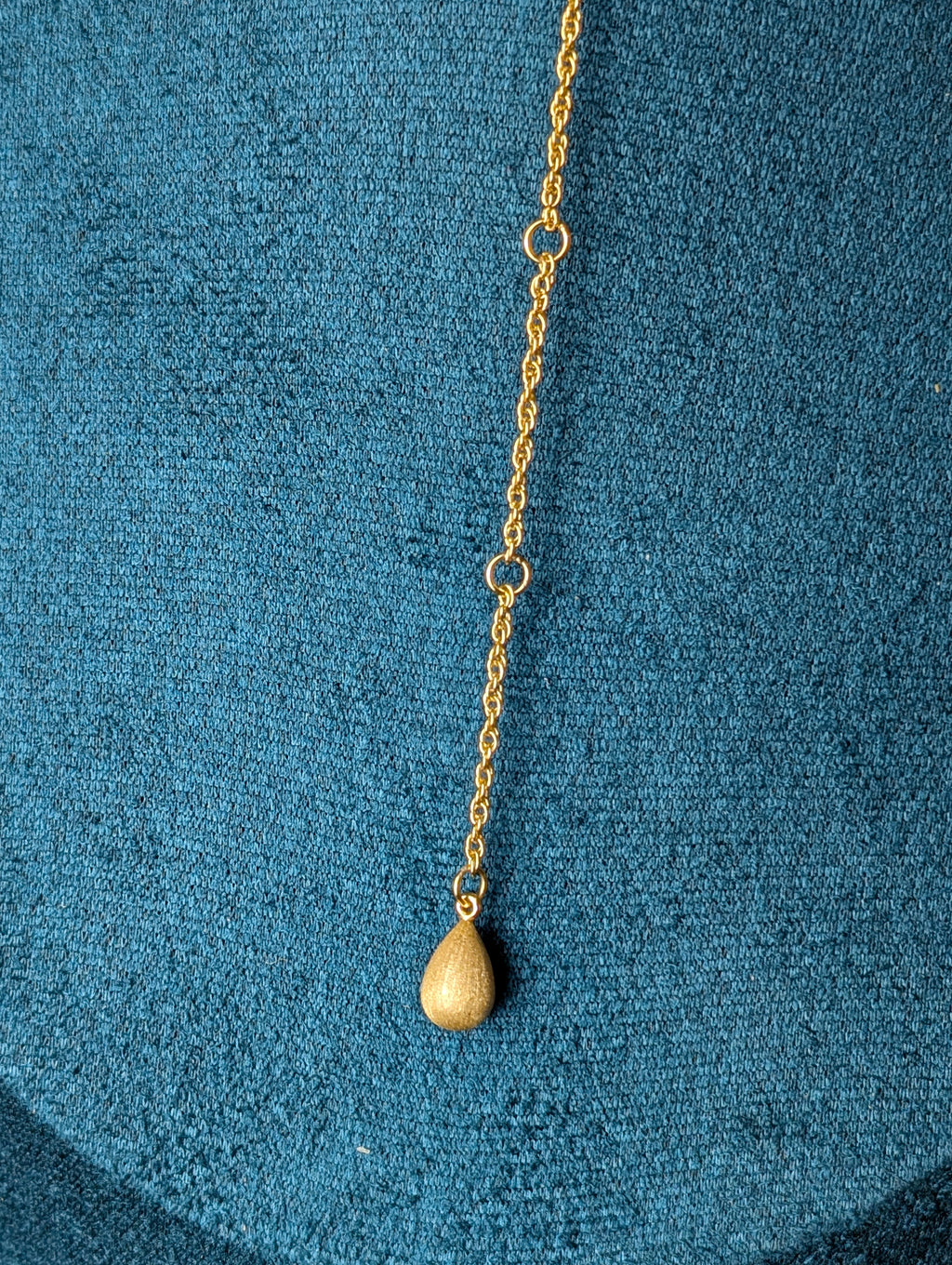 Nudie Kiss by Nudie – close-up studio photo showing the signature counterweight at the back of the necklace, resting against a green mannequin background.