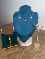 Jewelry display with necklace on blue velvet bust and earrings on stands.