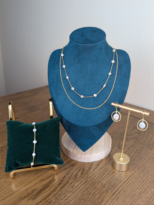Jewelry display with necklace on a blue bust, bracelet on a green pillow, and earrings on a gold stand.
