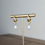 Gold earring stand with hanging earrings on a wooden surface