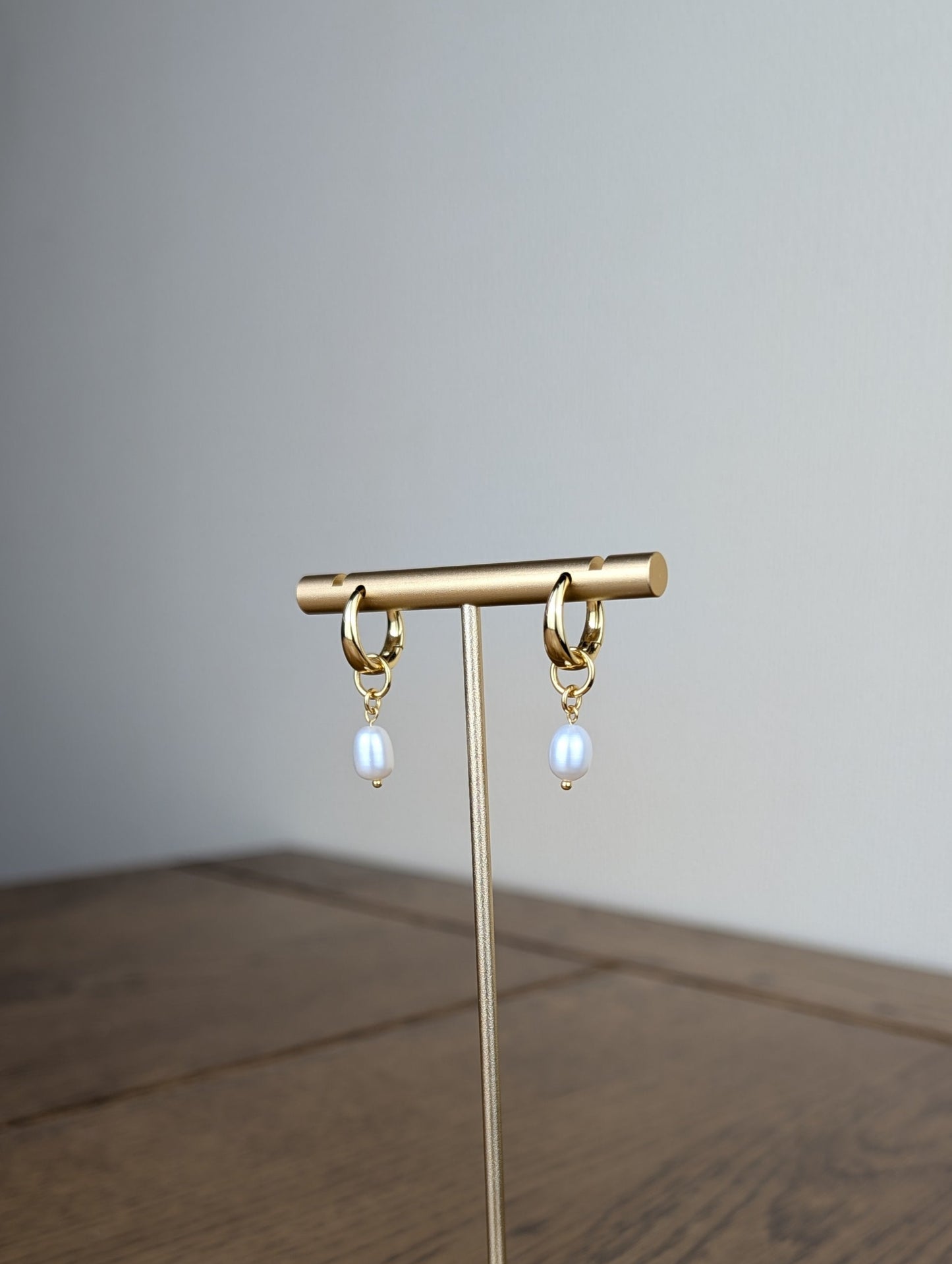 Gold earring stand with hanging earrings on a wooden surface