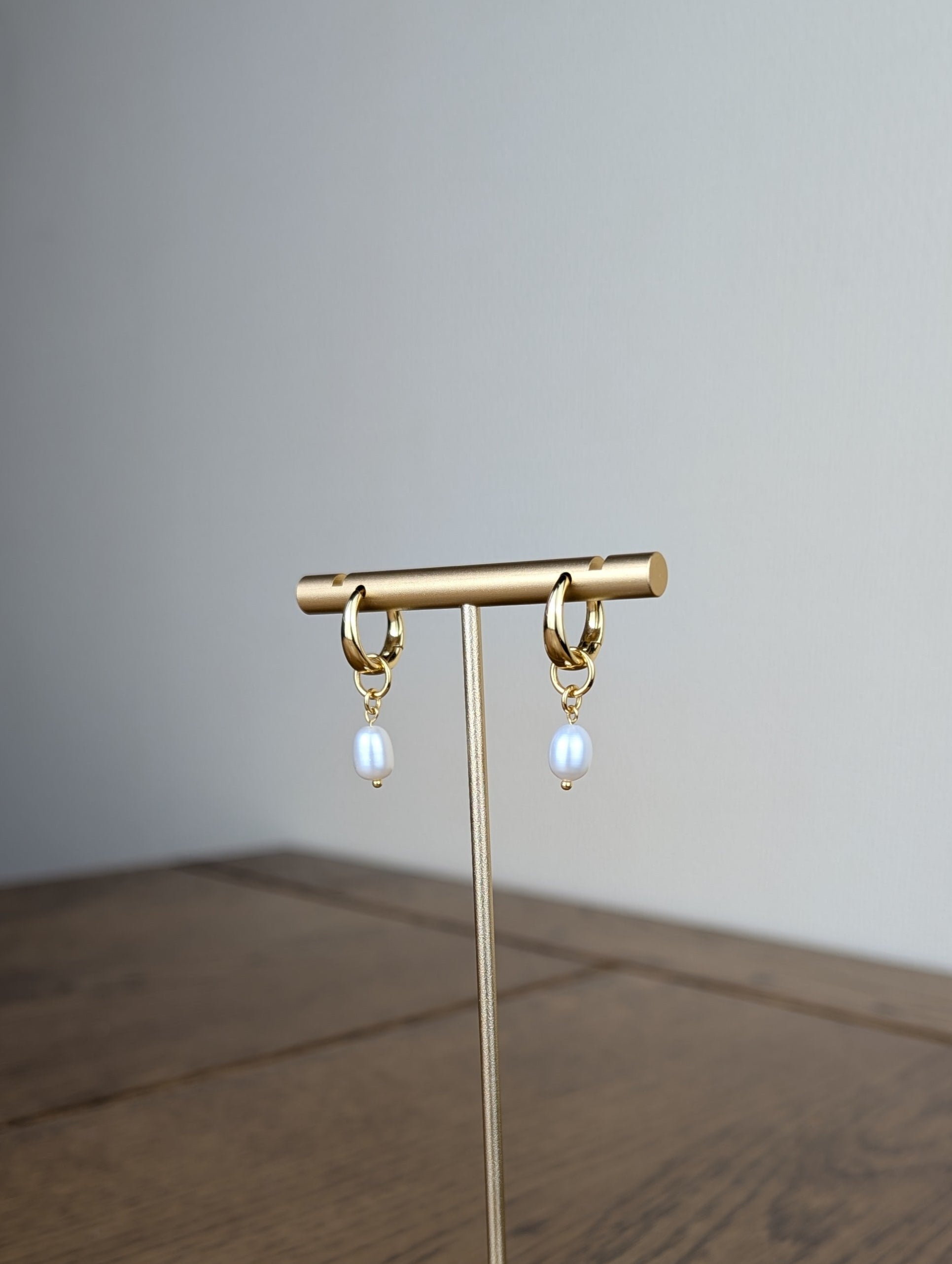 Gold earring stand with hanging earrings on a wooden surface
