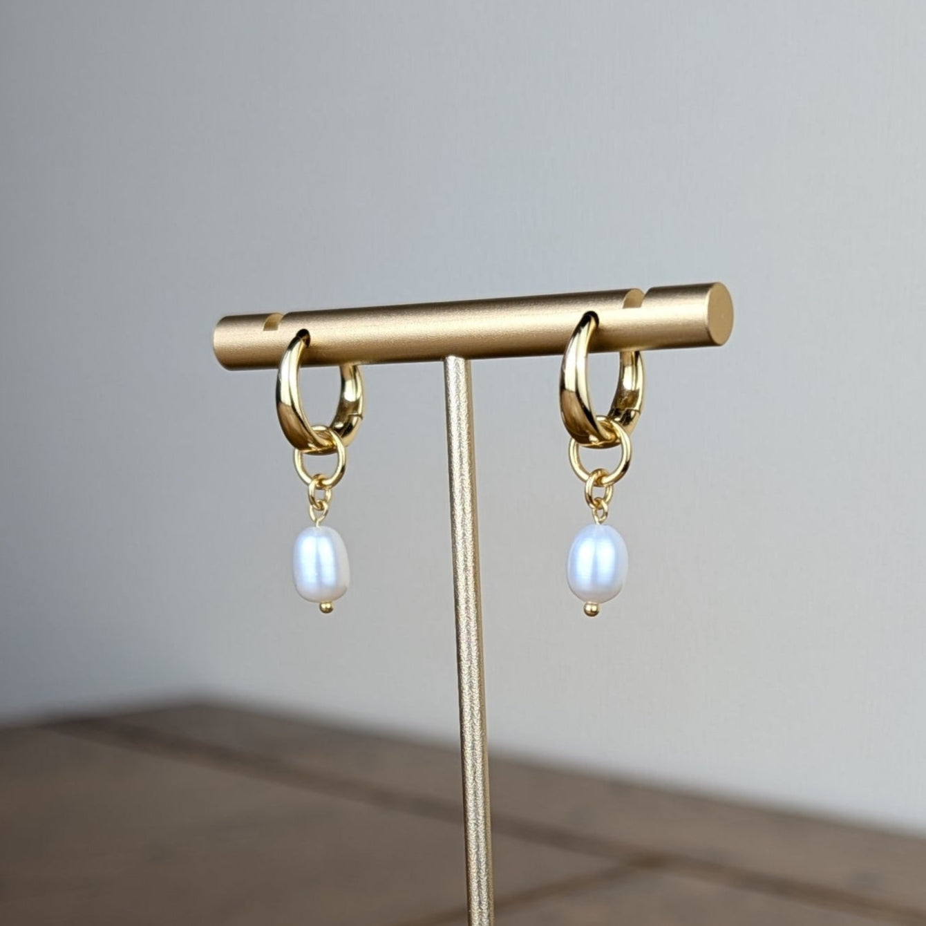 Gold earring stand with hanging earrings on a wooden surface