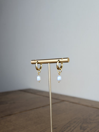 Gold earring stand with hanging earrings on a wooden surface
