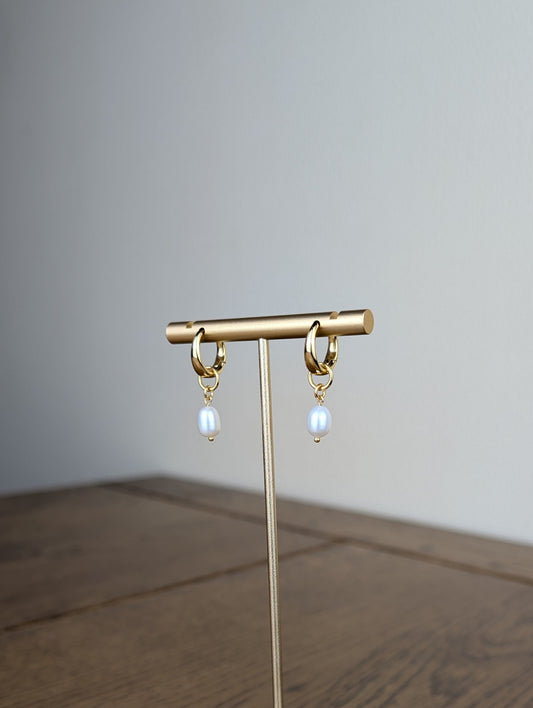 Gold earring stand with hanging earrings on a wooden surface