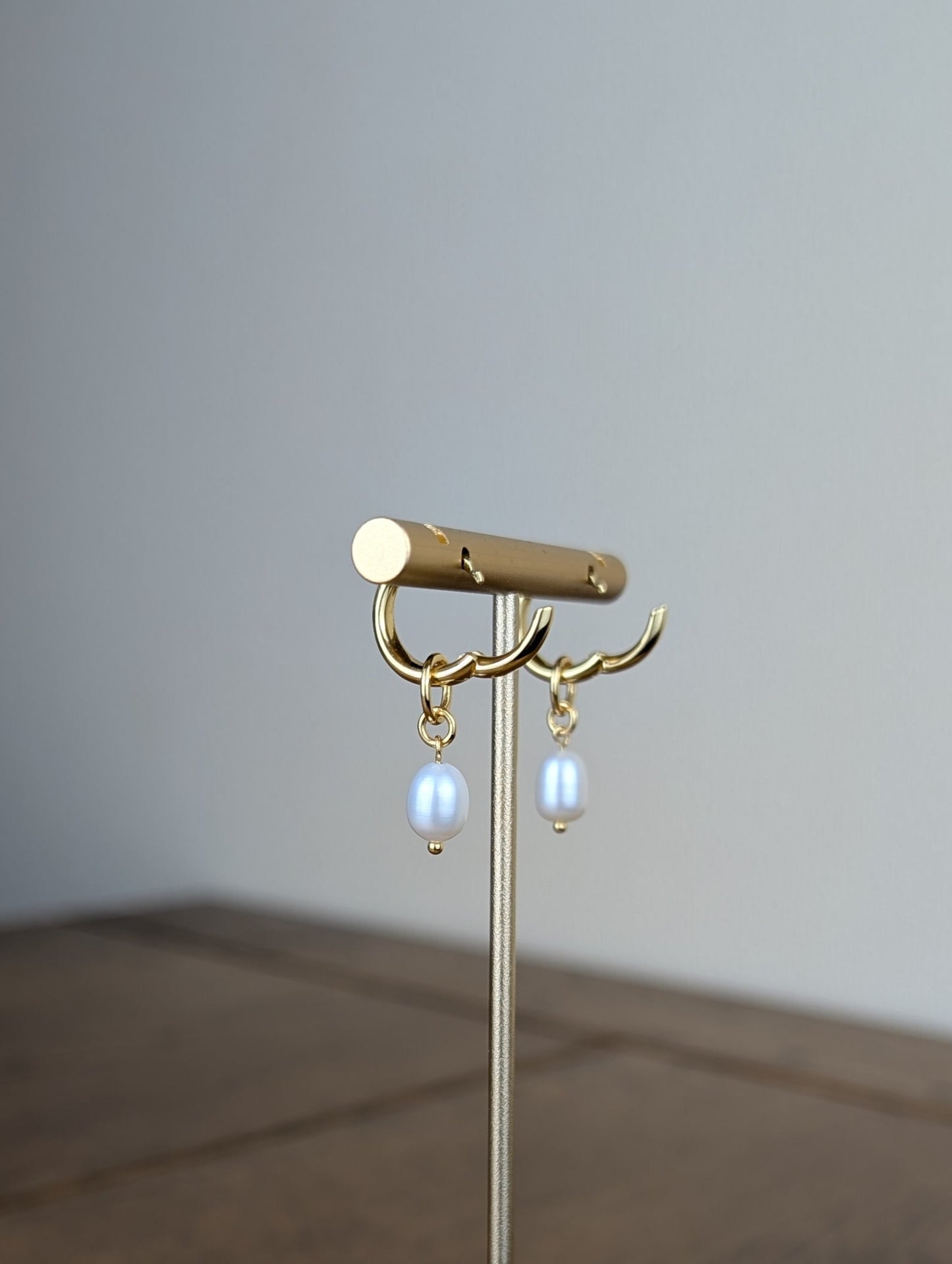 Gold jewelry stand with earrings on a wooden surface