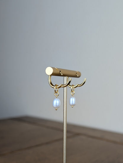 Gold jewelry stand with earrings on a wooden surface