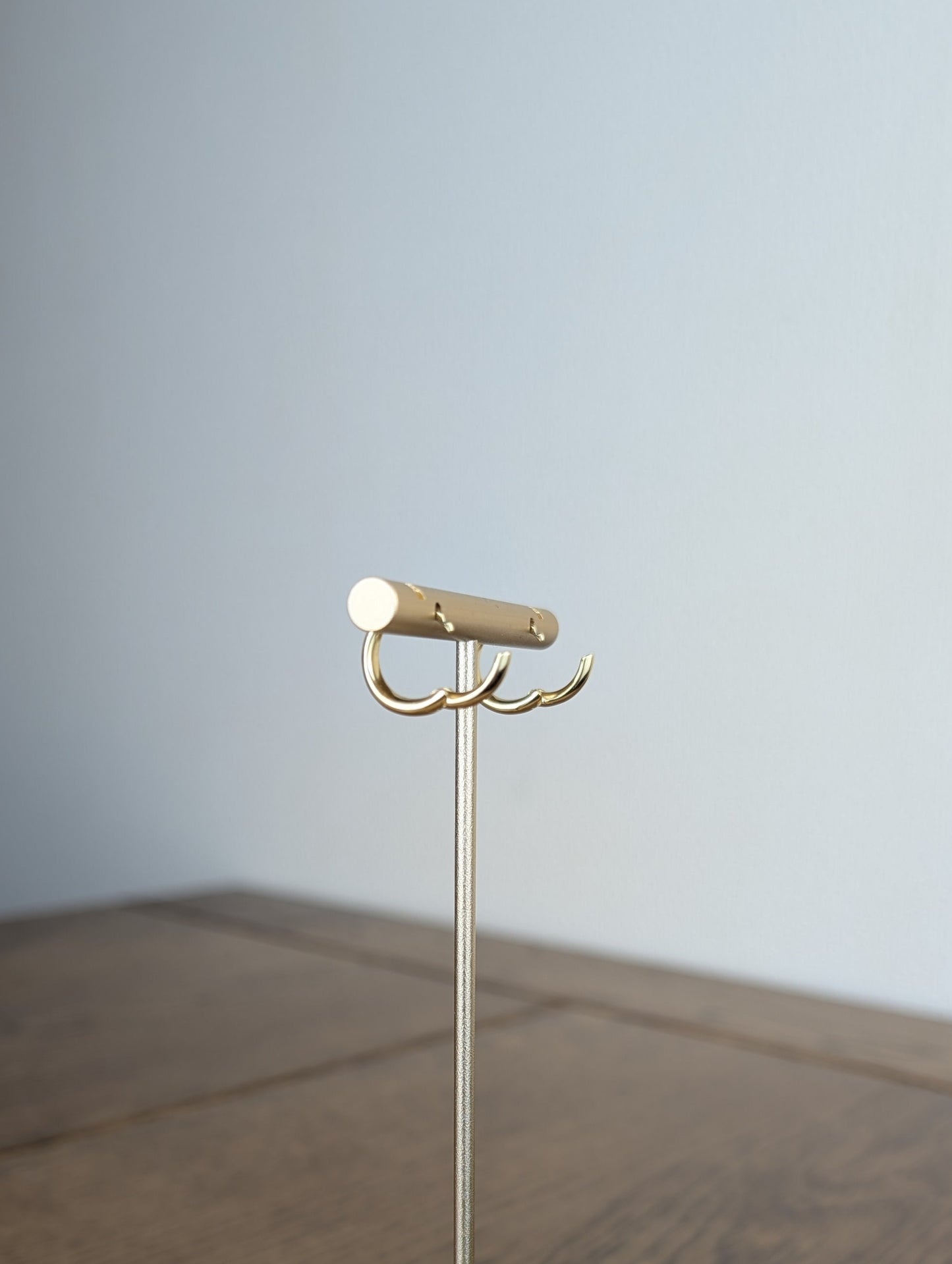 Gold jewelry stand on a wooden surface with a plain background