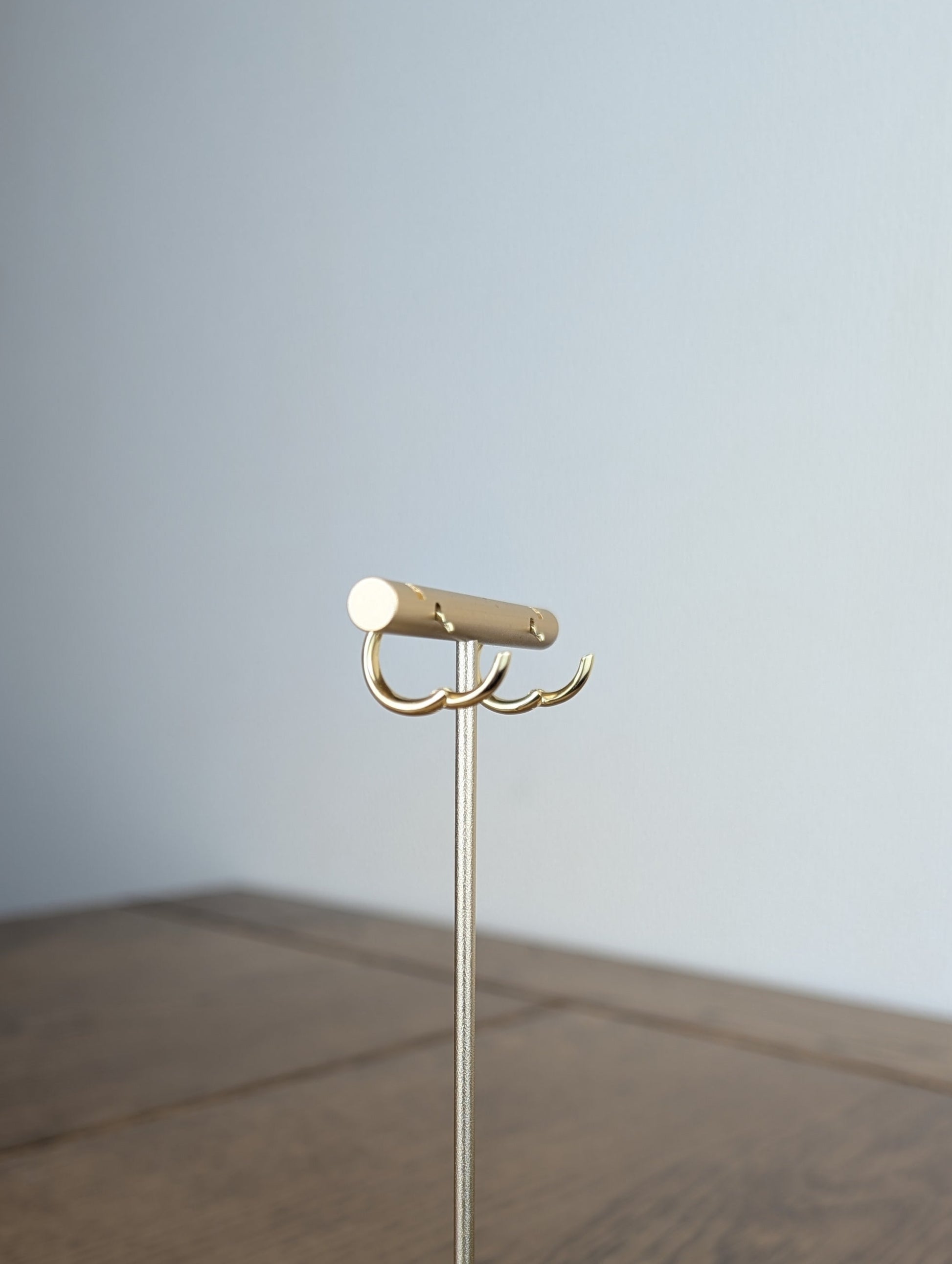 Gold jewelry stand on a wooden surface with a plain background