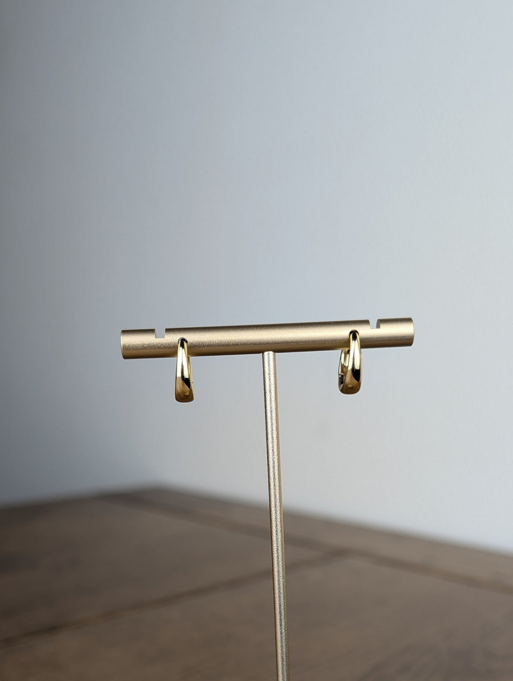 Gold jewelry stand on a wooden surface with a neutral background