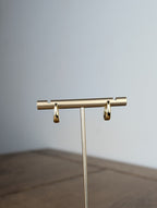 Gold jewelry stand on a wooden surface with a neutral background
