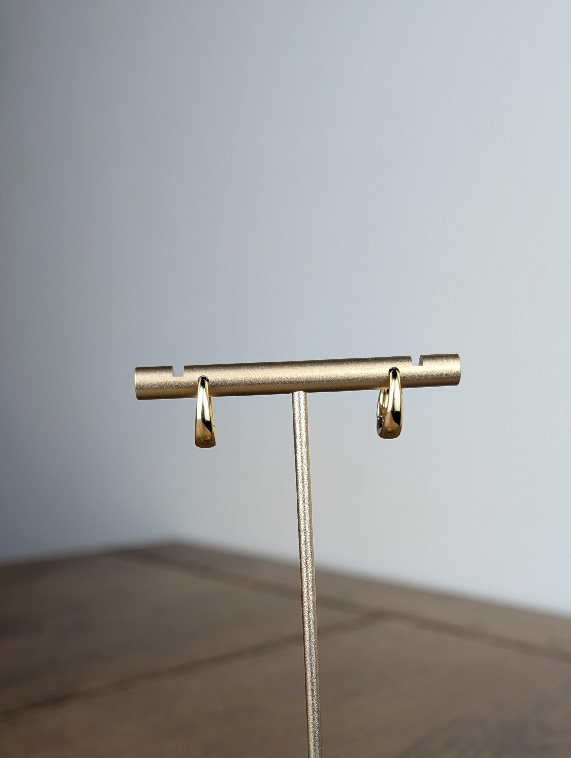 Gold jewelry stand on a wooden surface with a neutral background