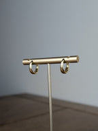 Gold jewelry stand on a wooden surface with a gray background