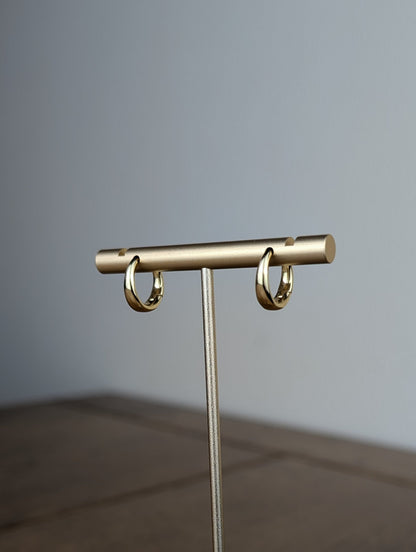Gold jewelry stand on a wooden surface with a gray background