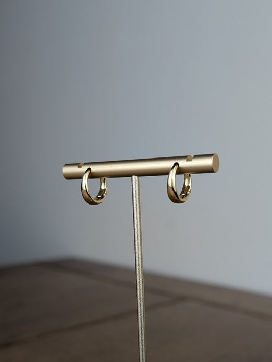 Gold jewelry stand on a wooden surface with a gray background