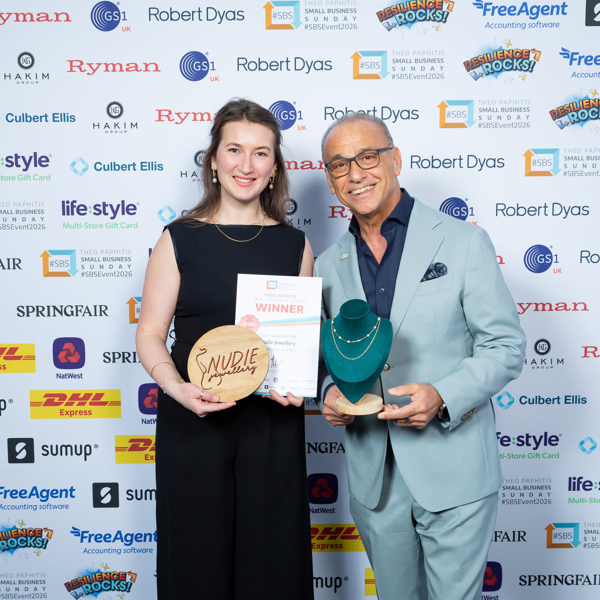Two people holding awards in front of a branded backdrop