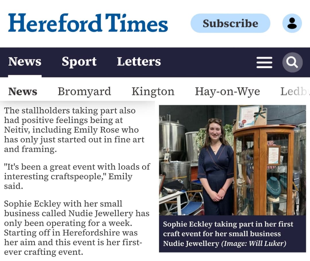Hereford Times feature on Neitiv Craft Fair – photo of Nudie Jewellery founder standing beside the Nudie event stand, with jewellery display and branding visible.
