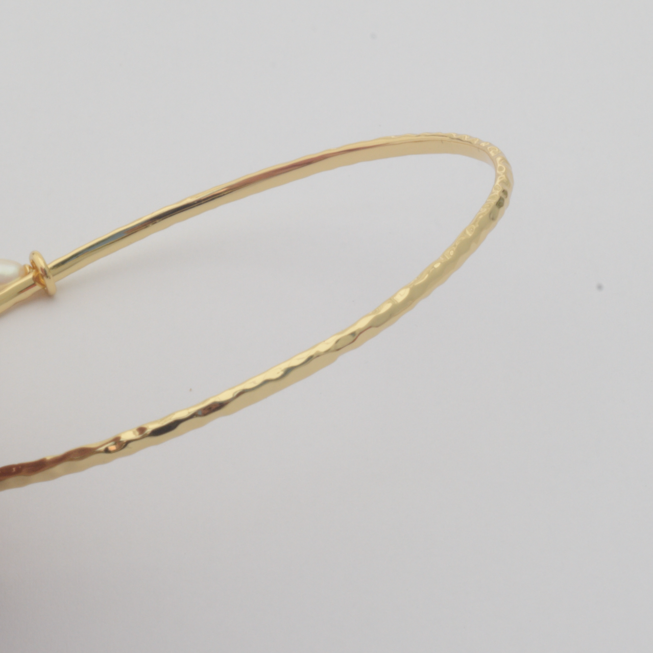 Nacre Bangle by Nudie – close-up studio photo on white background showing the hammered 18k gold-plated texture in detail.