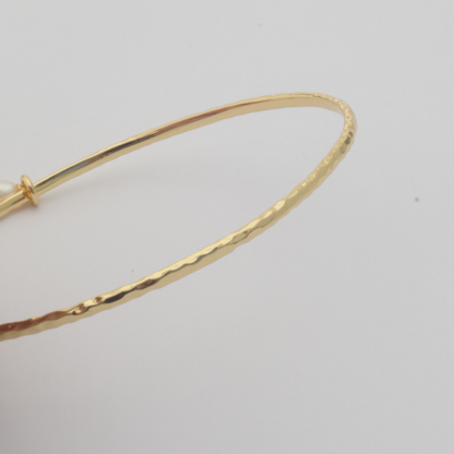 Nacre Bangle by Nudie – close-up studio photo on white background showing the hammered 18k gold-plated texture in detail.