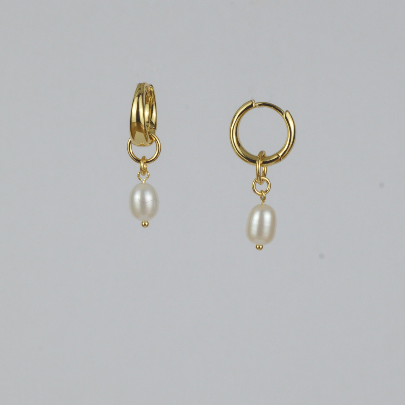 Perla Earrings by Nudie – studio photo showing one teardrop freshwater pearl earring front-on and one side-on, on white background with 18k gold hooks.