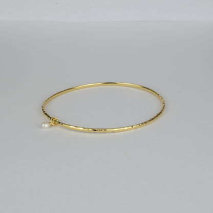 Nacre Bangle by Nudie – studio photo on white background showing the open bangle laid flat, featuring a petite freshwater pearl and hammered gold finish.